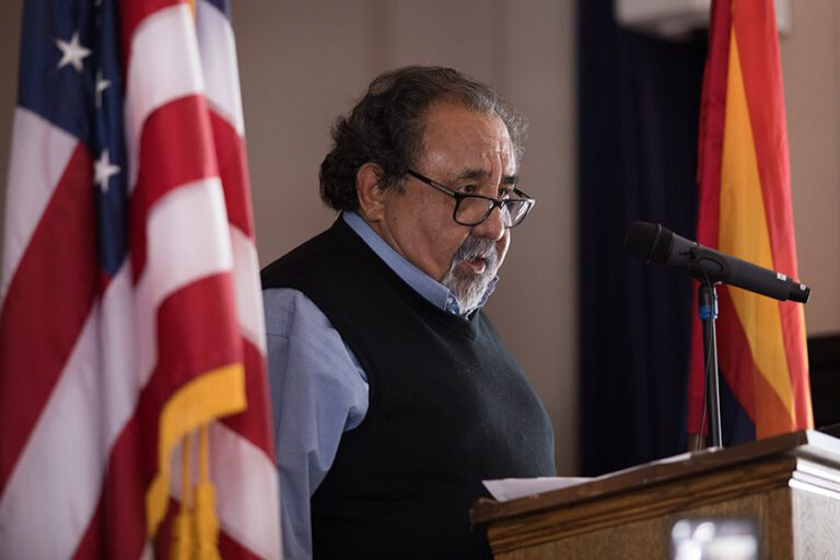 Congressman Raul Grijalva speaks at a podium with a microphone, flanked by U.S. and Arizona flags in 2019.
